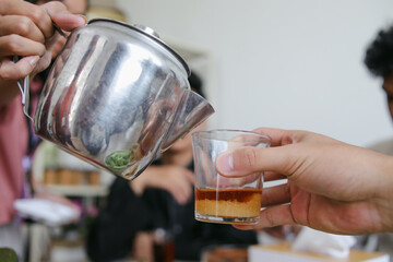 Muslim Man Pouring Tea To Break Fast During Ramadan Feasting Month at Dining Table