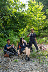 group of young asian men and woman drink from water bottle while resting after trekking and hiking in nature