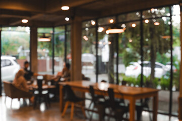 Blurry image of a cafe with people sitting at tables and chairs.