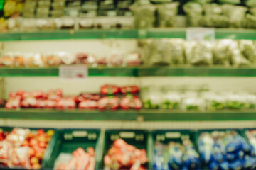 Blurry image of a grocery store with a lot of fruit and vegetables on display.