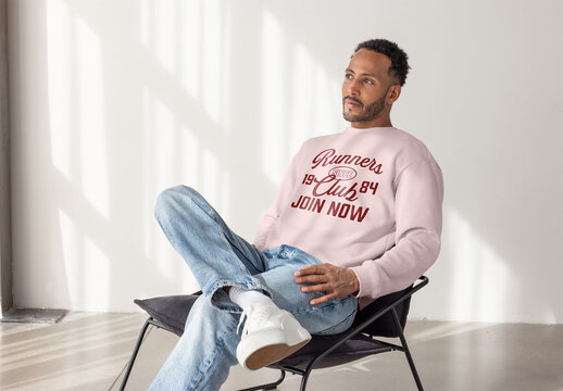 Stylish Black Man Wearing a Sweater Sits Thoughtfully Indoors