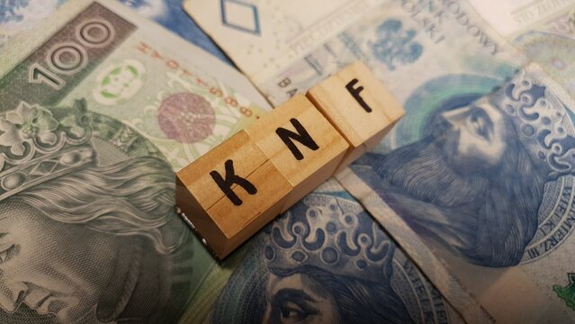 Polish PLN banknotes and KNF inscription made of letter cubes. Financial Supervision Authority