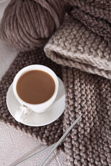 Cozy homely atmosphere. Hobby is knitting. Cup of coffee and knitting from wool yarn on table. Yarn of warm tones. Knitting process.