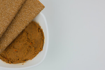 Close-up of a white plate with liver pate and bread on top on a white background with space for text. The concept of snacks, healthy food, diet. High quality photo