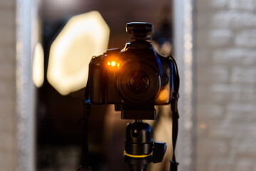 Professional digital camera on a tripod taking photo connected by a synchronizer to the flashlights at home.