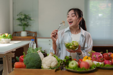 Young woman enjoying fresh salad at home surrounded by healthy food