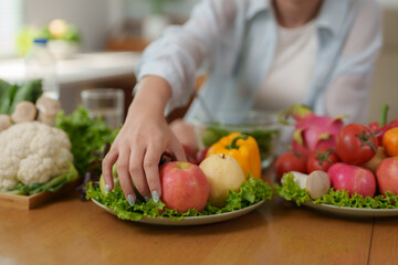 Woman preparing a plate of fresh fruit and vegetables for a healthy meal