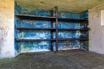Wooden shelving in a concrete storeroom at an abandoned WWII military bunker