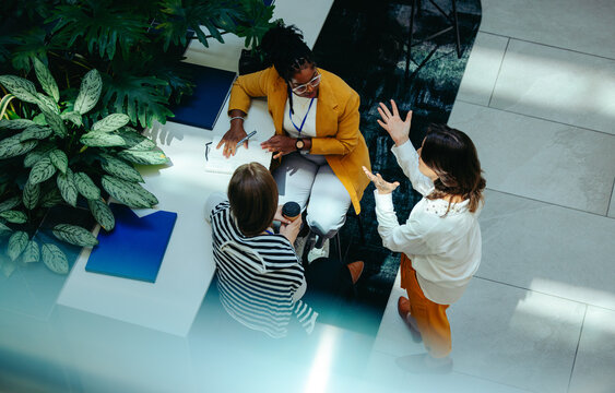Overhead view of female colleagues discussing in modern office