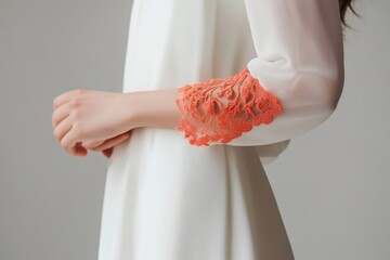 Close up of delicate coral lace sleeves on a flowing white dress, showcasing intricate details and modern bridal fashion
