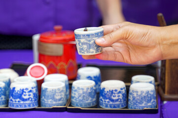 Hand holding blue Chinese art pattern teacup with blurred teacup set as background. Soft and selective focus.