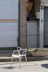 길거리에 놓인 하얀 플라스틱 의자의 모습  
