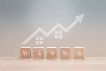 Wooden blocks with percentage symbols and increasing house prices showing positive growth in the...