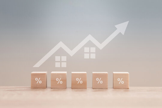 Wooden blocks with percentage symbols and increasing house prices showing positive growth in the real estate market