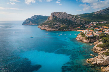 Obraz premium Scenic coastal view with boats anchored in turquoise waters near a charming village nestled in the cliffs