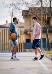 Two multiethnic basketball players talking and smiling on court