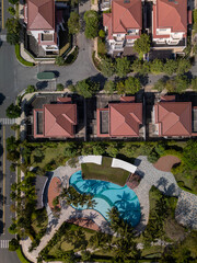 Modern, luxury Housing estate with swimming pool, houses, and villas in rows, beautiful landscaping on sunny, clear morning from top down vertical aerial view. Top down view.
