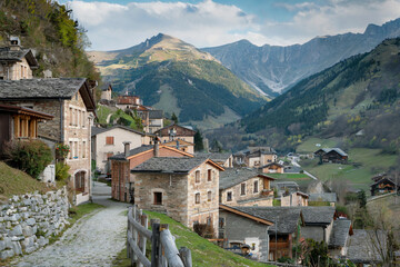 Picturesque village nestled in the mountains with stone houses and a serene pathway surrounded by lush greenery