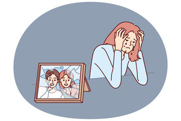 Woman cries after breaking up with husband and is sad sitting near broken photo with happy family. Widow girl cries and sheds tears after death of boyfriend causing emotional distress.