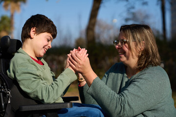 Happy child with disability playing with his educator outdoors - cerebral palsy concept