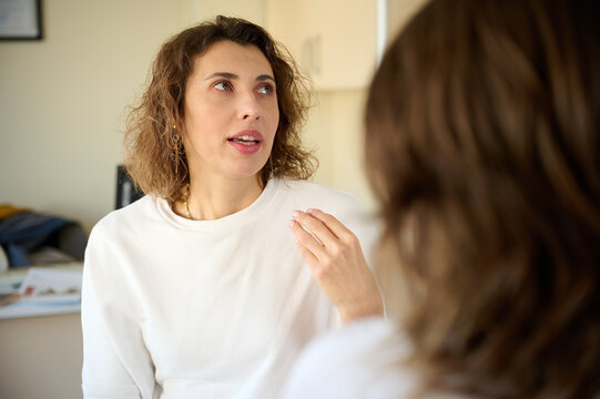 Female doctor consulting patient in treatment office room. Osteopathic medicine and physiotherapy concept. Conversation between two pretty girls. Communication between two women