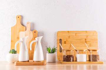 A storage area for spices in glass jars, oils in ceramic special bottles on a wooden countertop in the kitchen. Front view. Zero waste house concept