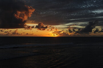 Dramatic sunset with clouds with orange sky on a sand beach over the Indian Ocean in Sri Lanka