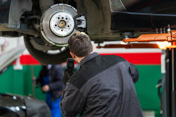 Serviceman checks the brake discs of a car