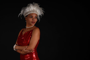 Low key portrait of young curly woman in red dress with headdress made of bird feathers