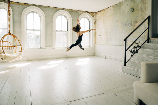 Ballet dancer leaps gracefully in a sunlit vintage dance studio