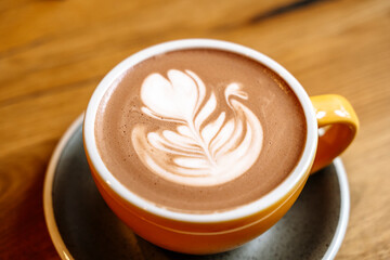 Cup of cocoa with milk art on wooden table in the morning at breakfast