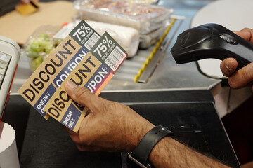 Closeup of unrecognizable cashier scanning discount coupons at supermarket checkout line, copy space