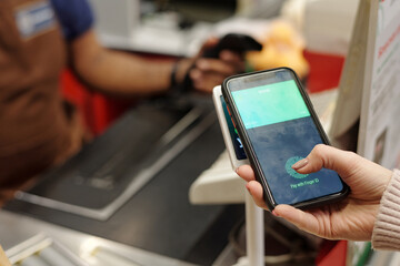 Closeup of female hand paying vis smartphone at supermarket checkout and scanning fingerprint for data and finance security, copy space