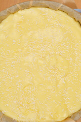 A top-down view of a light yellow vanilla and coconut cream cake filling set in a blue baking dish lined with parchment paper