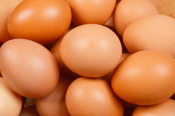 A close-up shot of a pile of brown eggs, showcasing their natural texture and color variations