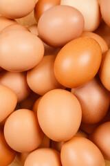 A close-up shot of a pile of brown eggs, showcasing their natural texture and color variations