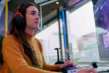 Gamer wearing headphones playing video game on computer in a gaming room