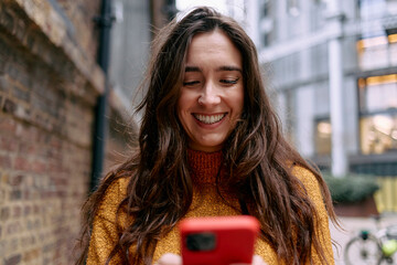 Woman smiling while using smartphone in urban setting