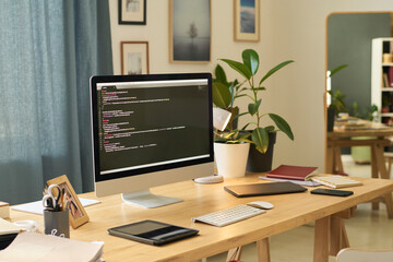 Home office workspace of a programmer with a computer screen displaying code