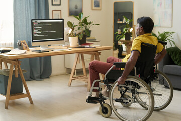 Freelance worker in wheelchair coding at home office