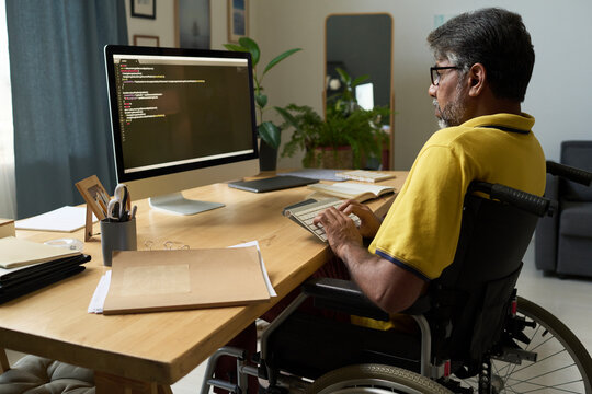Man with disability writing script on computer at home office