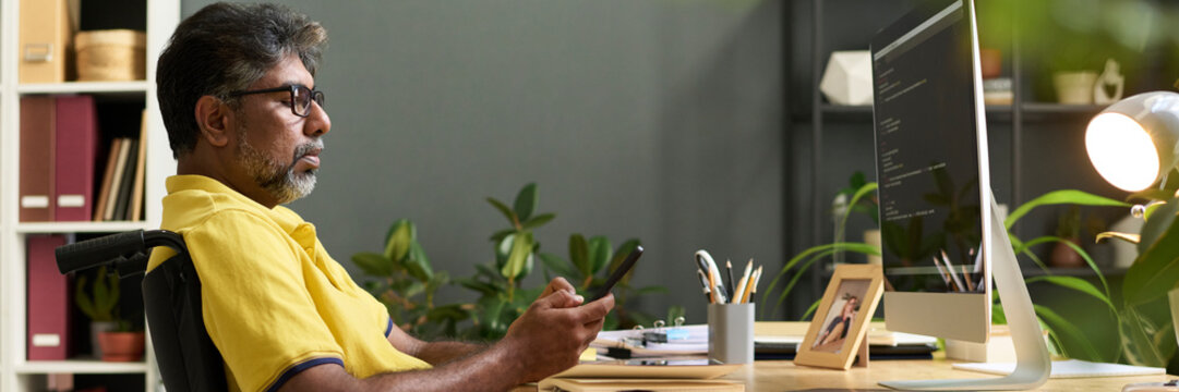 Man in a wheelchair working on programming at home office