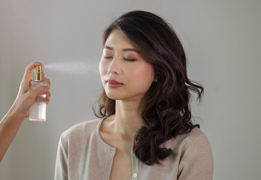 Makeup artist applying face mist to a client indoors