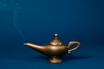 Magic lamp with smoke in a studio setting on a blue background