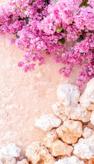 Pink flowers cascade over beach rocks on beige background