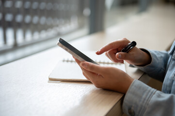 A close up of the left hand holding smartphone and right hand pointing at the phone screen.
