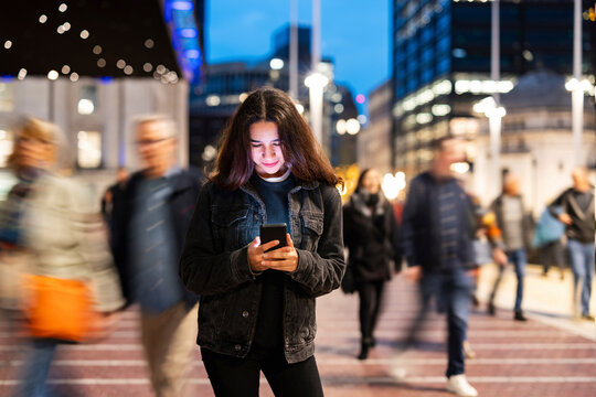 Woman using smartphone in busy city street during rush hour