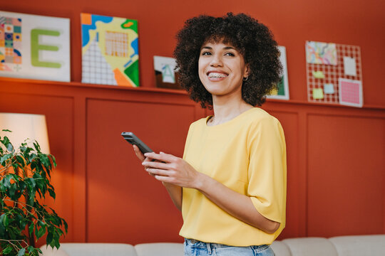 Smiling woman using smartphone in a colourful design studio