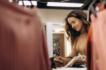 Smiling Woman Sorting Clothes in a Fashion Retail Setting