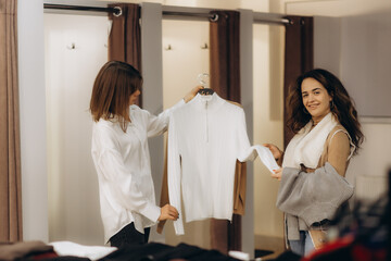 Two Women Shopping and Choosing Clothes in a Modern Fashion Store